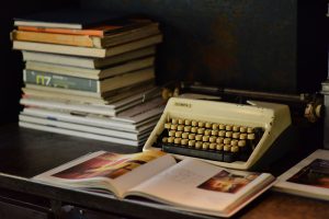 Home A nostalgic scene with an old typewriter and a stack of books on a wooden desk.